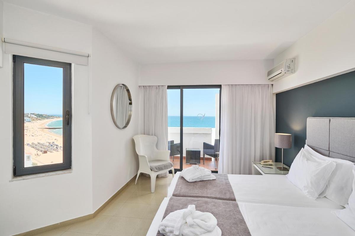 um quarto de hotel com uma cama e vista para o oceano em Rocamar Exclusive Hotel & Spa - Adults Only em Albufeira um quarto de hotel com uma cama e vista para o oceano em Rocamar Exclusive Hotel & Spa - Adults Only em Albufeira
