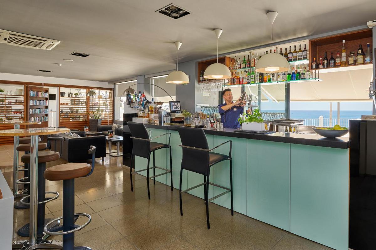 uma mulher parada em um bar em um restaurante em Rocamar Exclusive Hotel & Spa - Adults Only em Albufeira