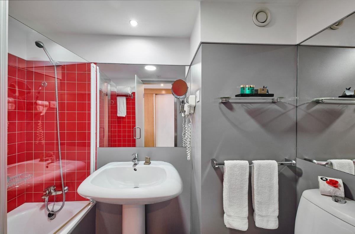 uma casa de banho com um lavatório e uma parede de azulejos vermelhos em Rocamar Exclusive Hotel & Spa - Adults Only em Albufeira uma casa de banho com um lavatório e uma parede de azulejos vermelhos em Rocamar Exclusive Hotel & Spa - Adults Only em Albufeira