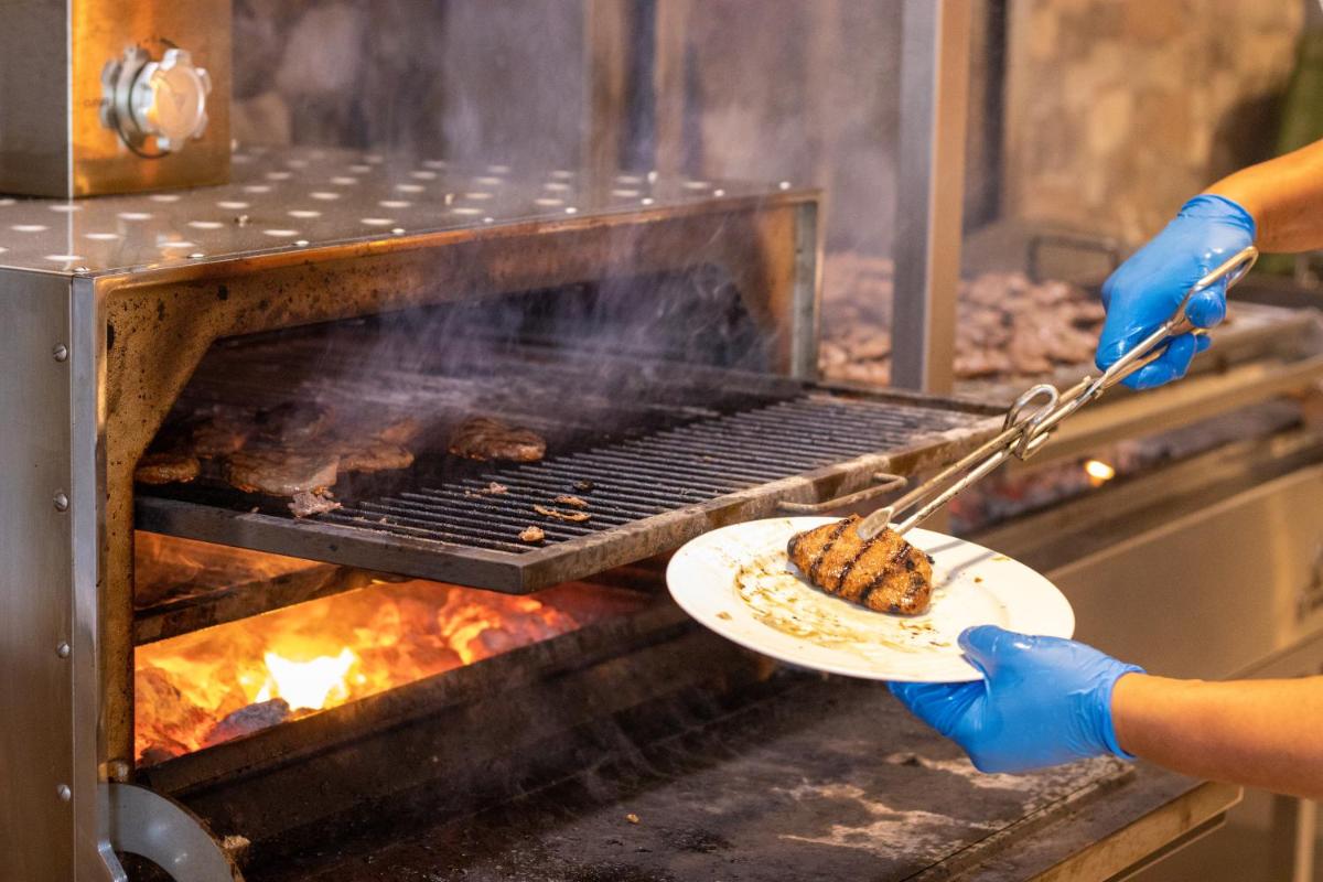 una persona que sostiene un plato de comida en una parrilla en Ohtels Islantilla, en Islantilla