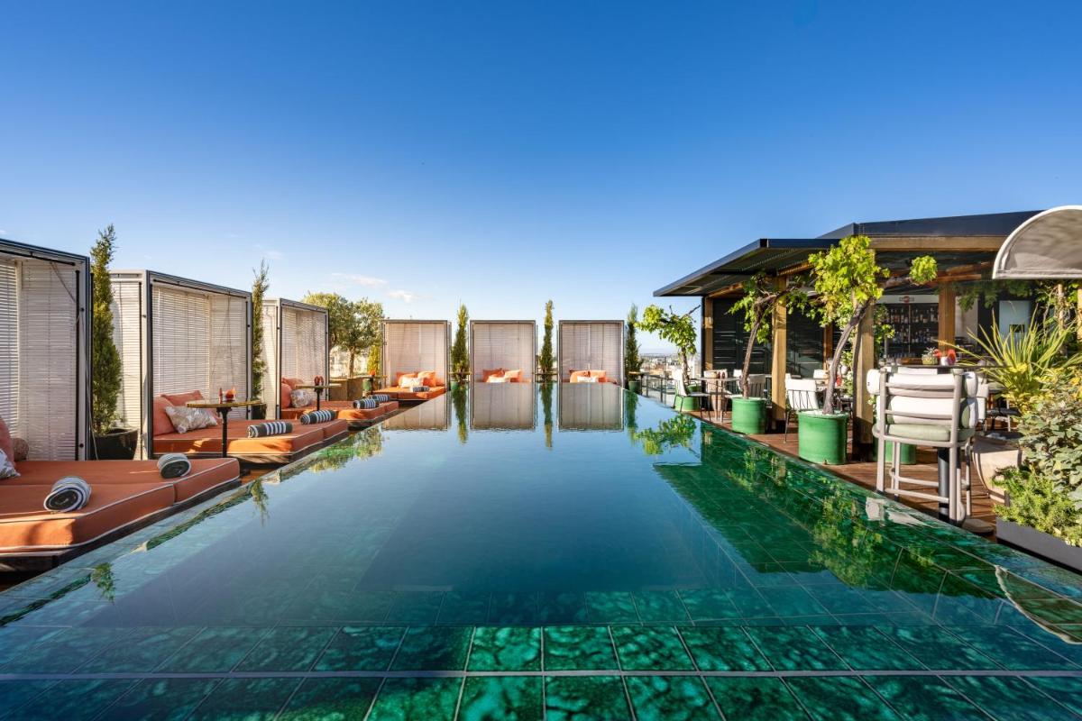 Una piscina infinita con tumbonas y un resort. en BLESS Hotel Madrid - The Leading Hotels of the World, en Madrid