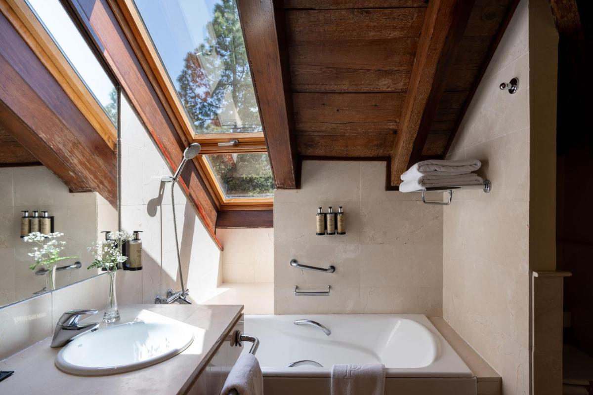 Un baño con bañera, lavabo y ventana. en Parador de Cruz de Tejeda, en Tejeda 53 fotos más