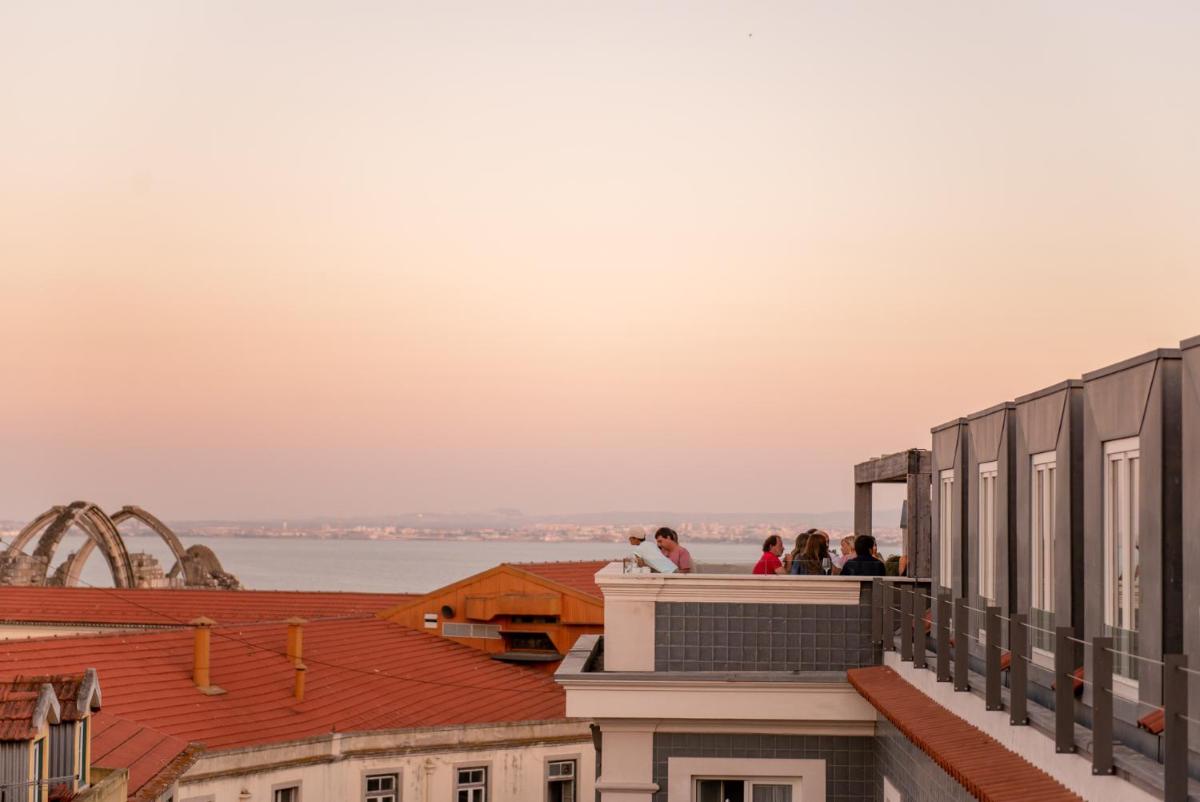 Pessoas no telhado de um prédio olhando para a água. em Lisboa Pessoa Hotel em Lisboa