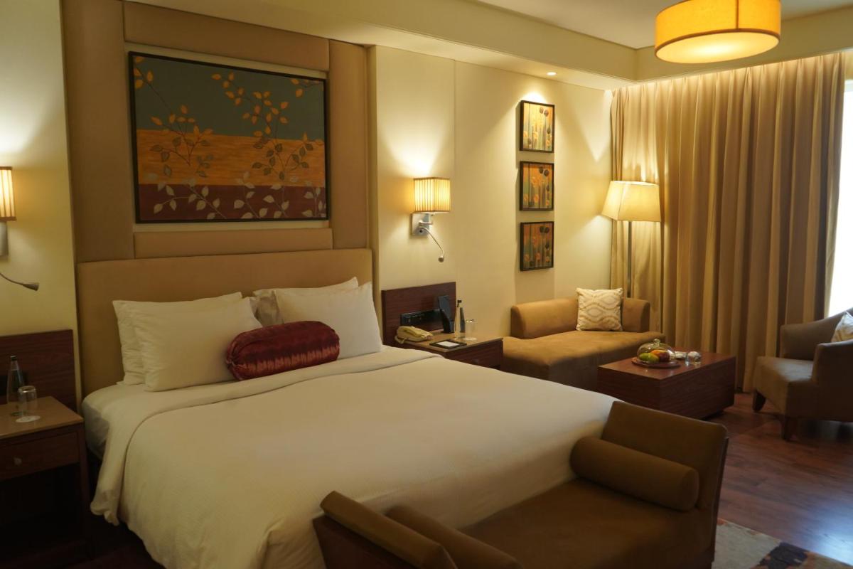 a hotel room with a large bed and a chair at DoubleTree by Hilton Agra in Agra