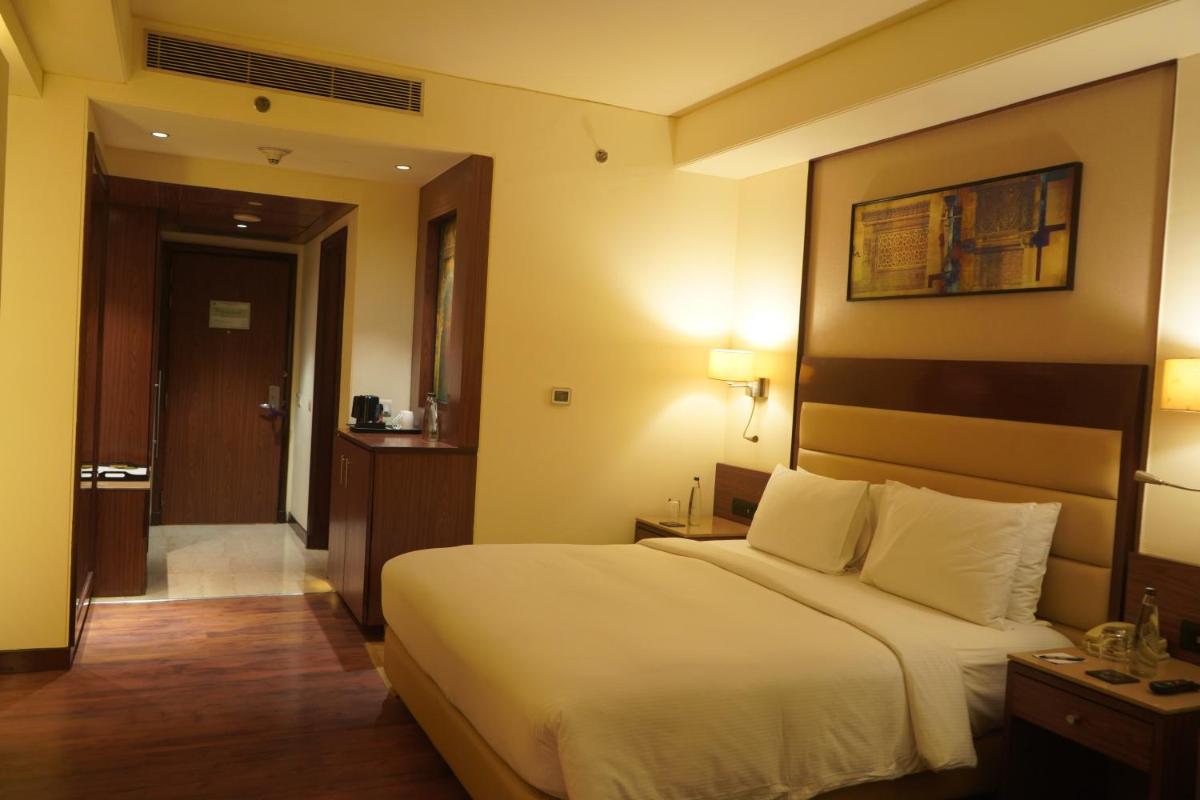 a hotel room with a large bed and a hallway at DoubleTree by Hilton Agra in Agra