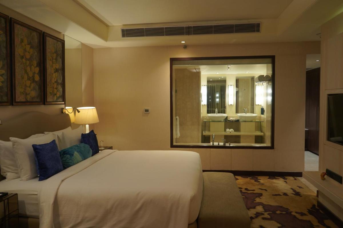 a bedroom with a large bed and a large mirror at DoubleTree by Hilton Agra in Agra