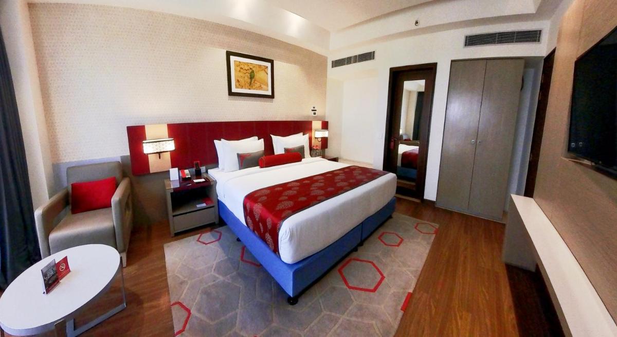 a bedroom with a bed and a table and a chair at Ramada Plaza by Wyndham Lucknow in Lucknow