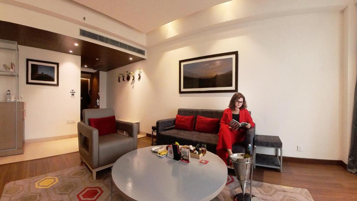 a woman sitting on a couch in a living room at Ramada Plaza by Wyndham Lucknow in Lucknow