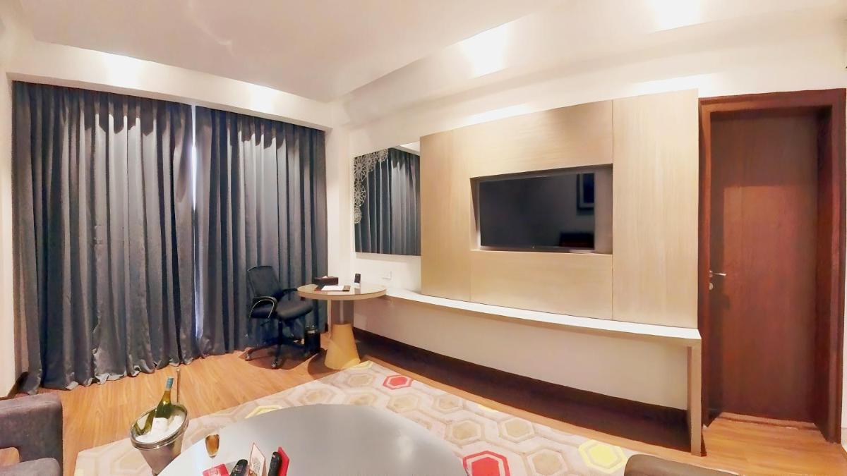 a living room with a tv on a wall at Ramada Plaza by Wyndham Lucknow in Lucknow