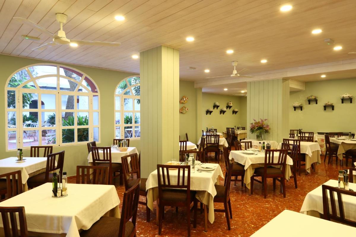 Un comedor con mesas y sillas blancas. en Hotel Varinia Serena - Balneario de Alange, en Alange