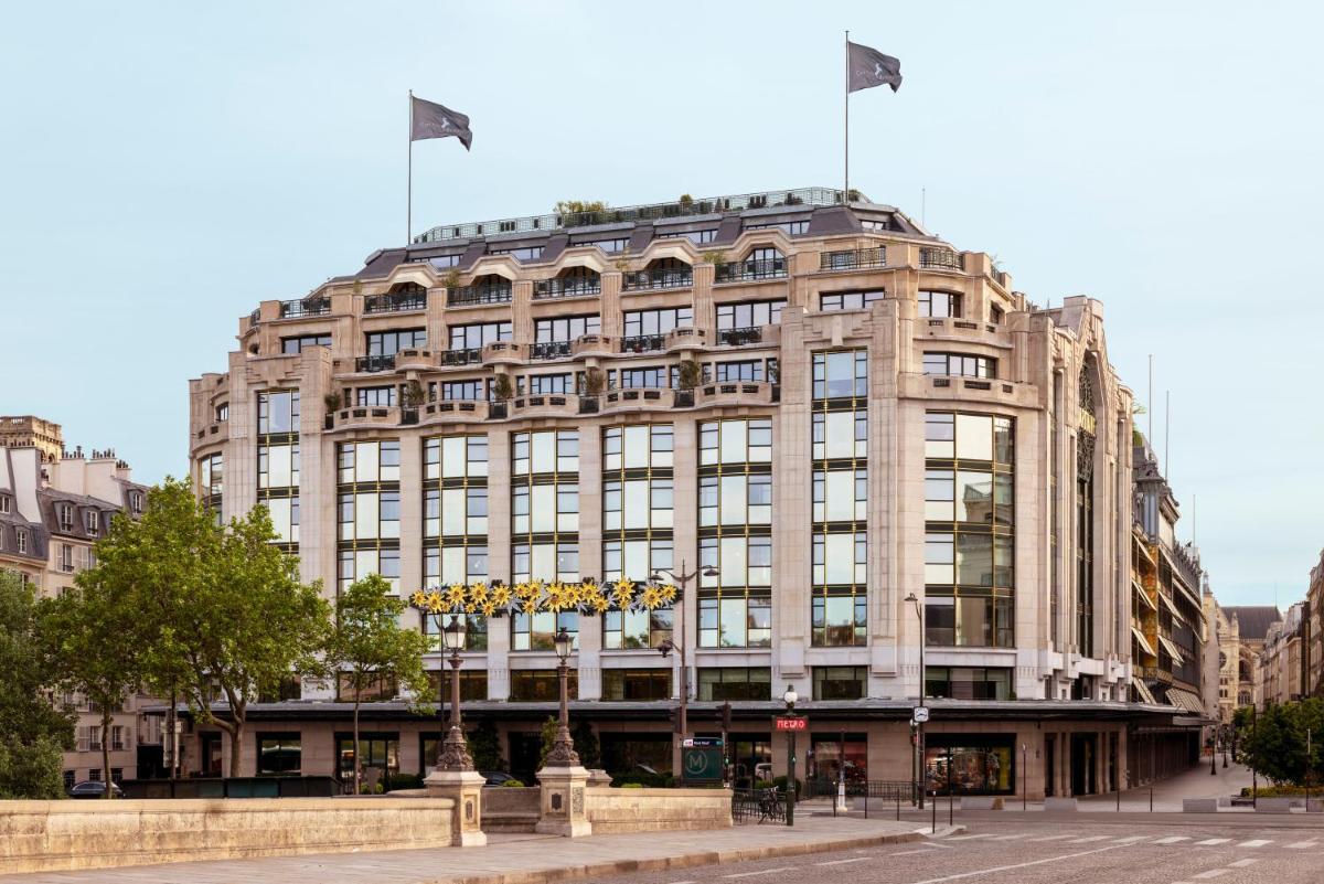 un grand bâtiment avec deux drapeaux en haut dans l'établissement Cheval Blanc Paris & Dior Spa Cheval Blanc Paris, à Paris