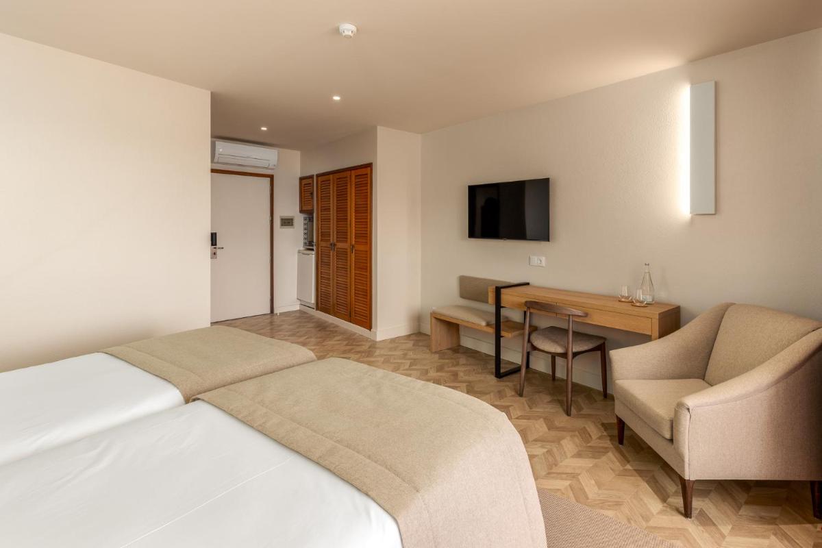 um quarto de hotel com uma cama, uma escrivaninha e uma televisão em Belavista Da Luz - Wellness & Lifestyle Hotel na Praia da Luz