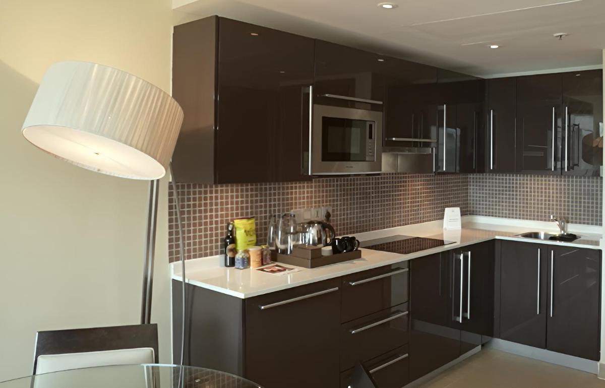 a kitchen with black cabinets and a table and a lamp at Hilton Bangalore Embassy GolfLinks in Bengaluru