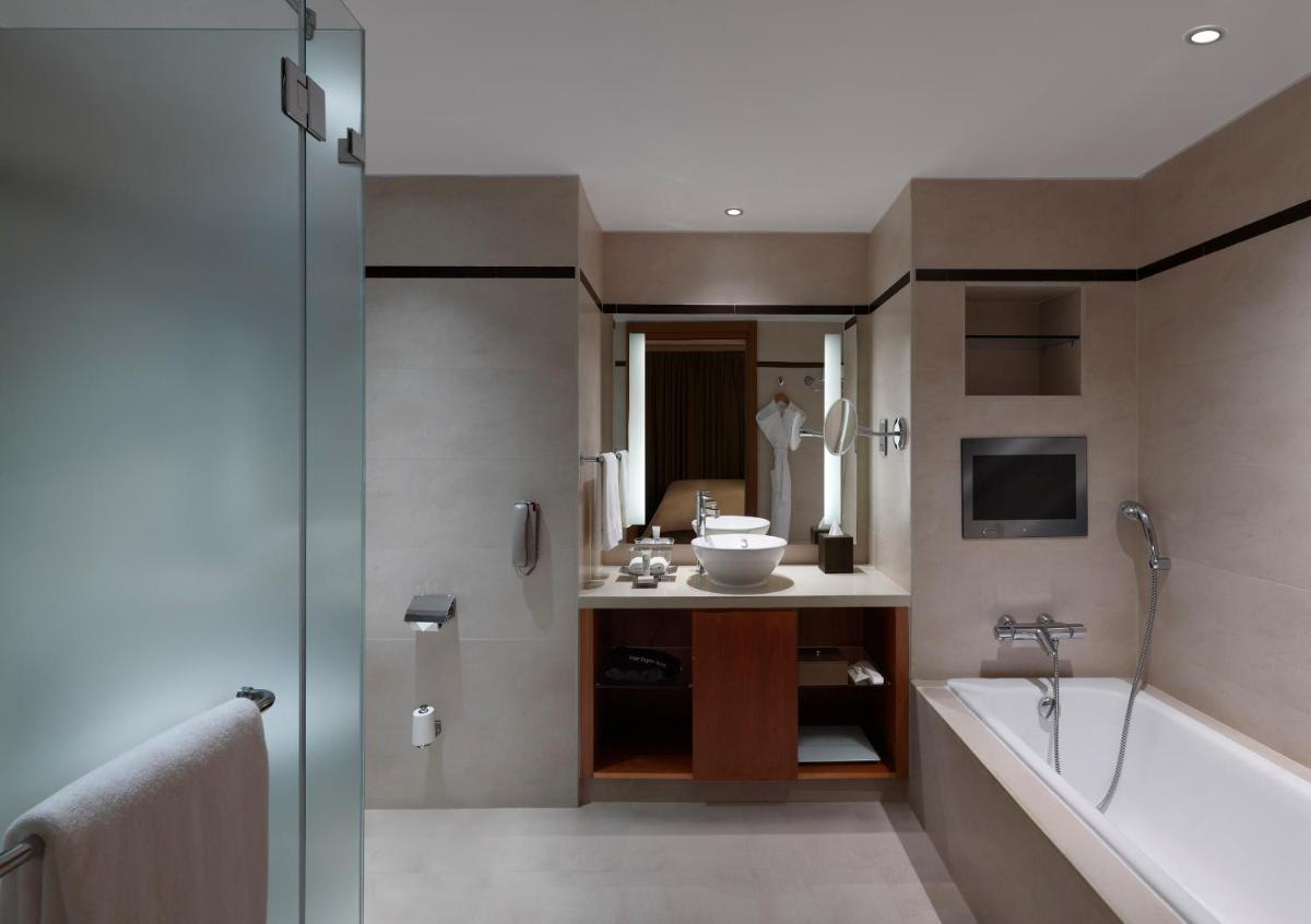 a bathroom with a tub and a sink and a bath tub at Hilton Bangalore Embassy GolfLinks in Bengaluru a bathroom with a tub and a sink and a bath tub at Hilton Bangalore Embassy GolfLinks in Bengaluru
