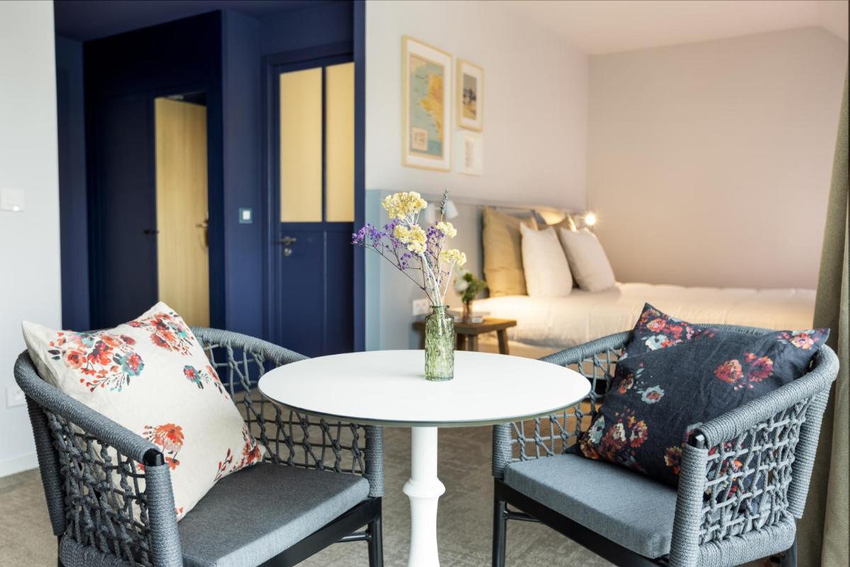 un salon avec une table, des chaises et un lit dans l'établissement Eco-Domaine La Fontaine - HOTEL-SPA - 300 m Plage de la Fontaine aux Bretons, à Pornic 111 autres photos