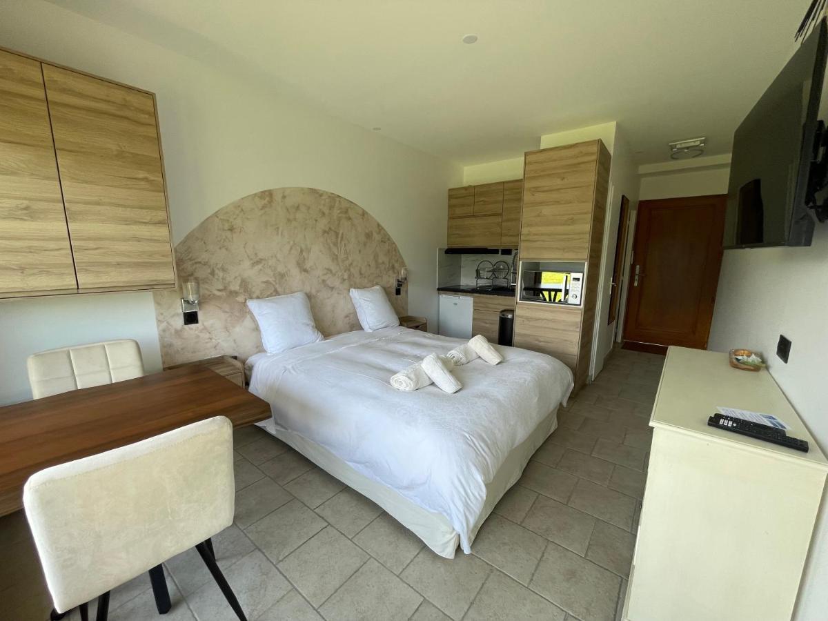 une chambre avec un grand lit blanc et une cuisine dans l'établissement La Parenthèse Enchantée, à Sévrier
