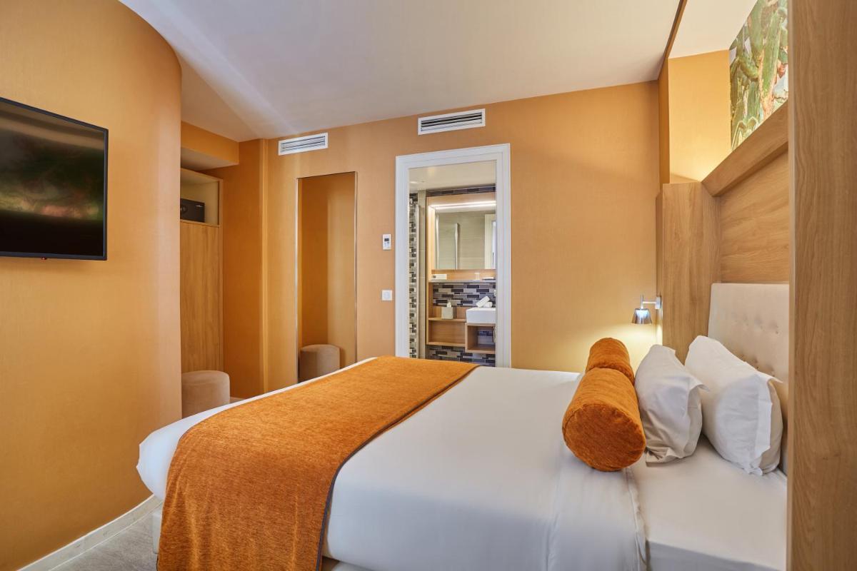 une chambre avec un grand lit blanc et des oreillers blancs dans l'établissement Jardins de Mademoiselle Hôtel & Spa, à Paris