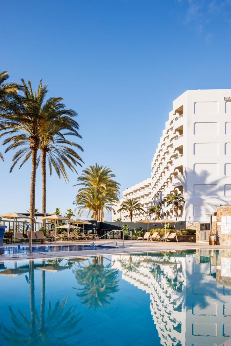 Una piscina con palmeras y un edificio. en Hapimag San Agustín, en San Agustín