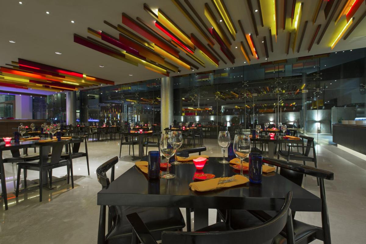 a restaurant with black tables and chairs and lights at The Westin Mumbai Garden City in Mumbai