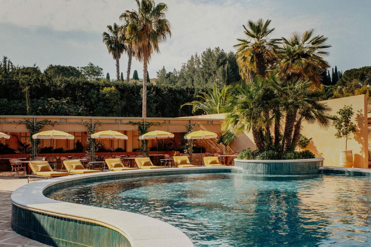 une piscine avec chaises longues et parasols dans un complexe hôtelier dans l'établissement Le Mas Candille, à Mougins