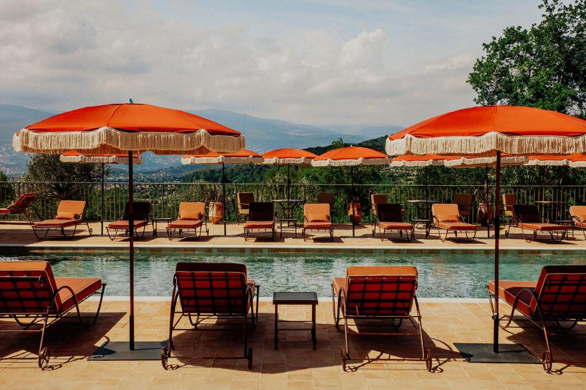 un groupe de chaises et de parasols à côté d'une piscine dans l'établissement Le Mas Candille, à Mougins