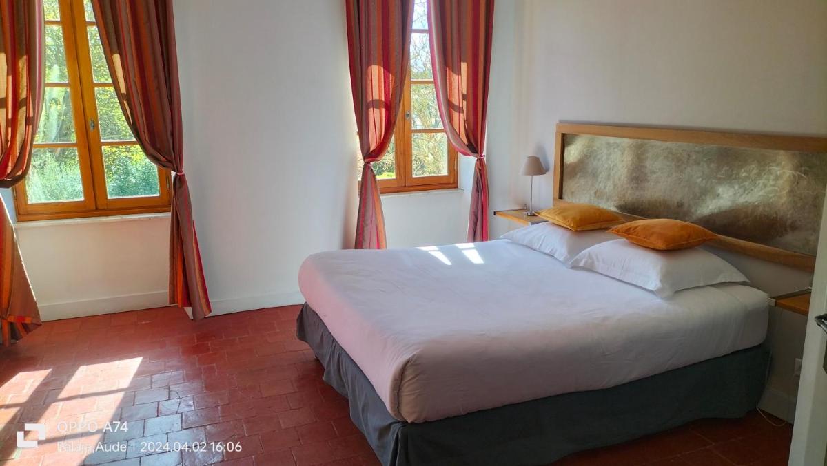 - une chambre avec un grand lit dans une pièce dotée de fenêtres dans l'établissement Logis Hôtel Château De Palaja, à Carcassonne