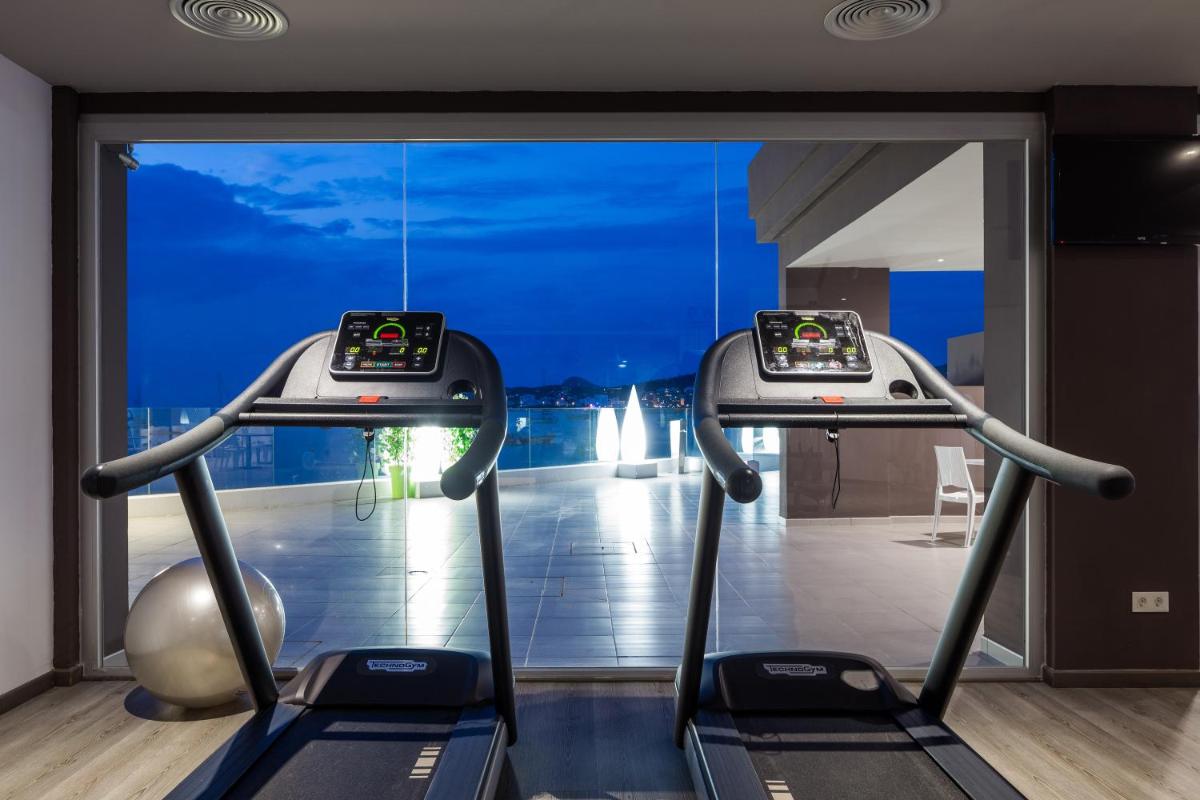 un gimnasio con dos cintas de correr frente a una ventana en Axel Beach Ibiza - Adults Only, en Bahía de San Antonio