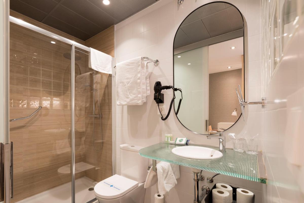 Un baño con lavabo, ducha y espejo. en Hotel Avenida, en A Coruña 68 fotos más