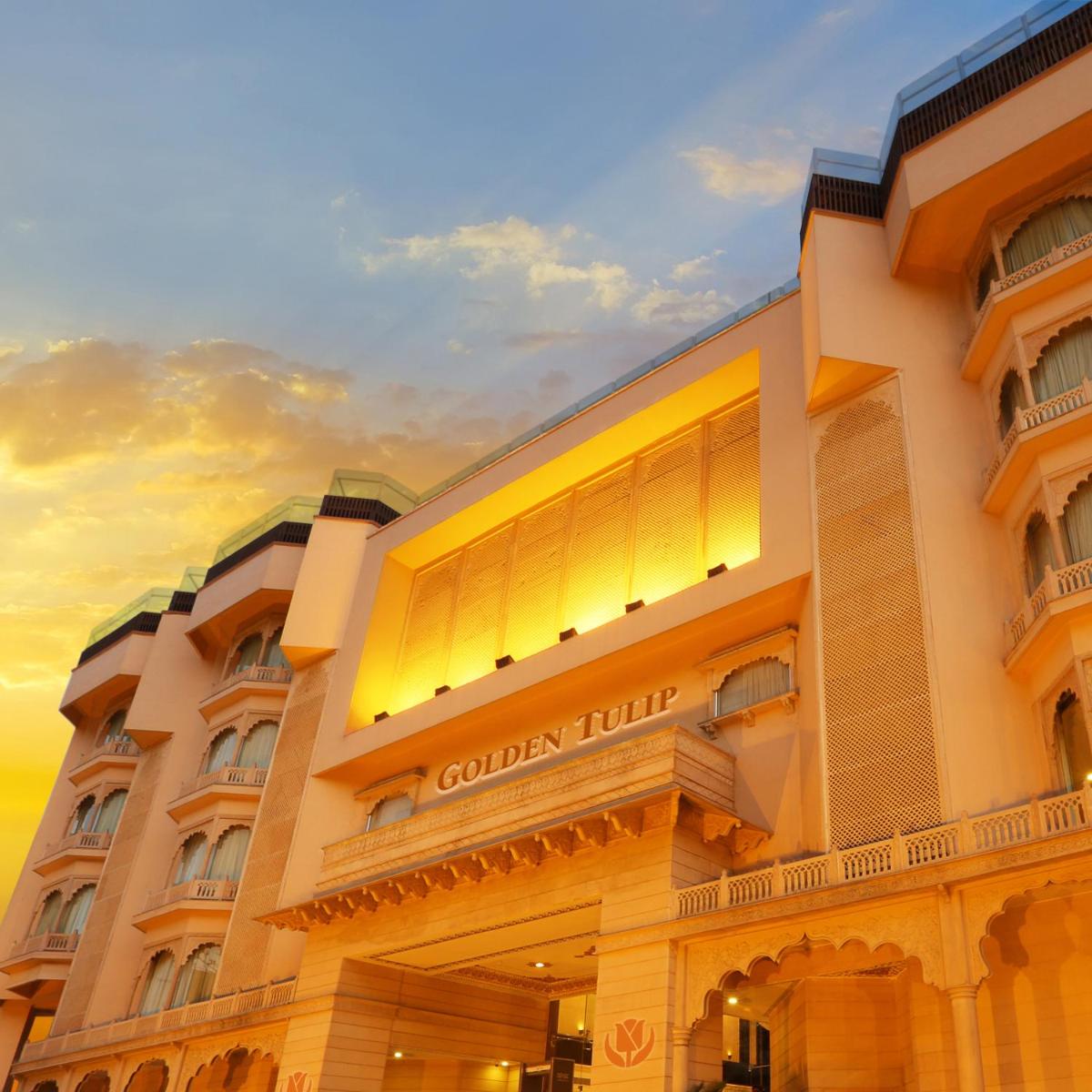 a hotel building with a sunset in the background at Golden Tulip Jaipur in Jaipur