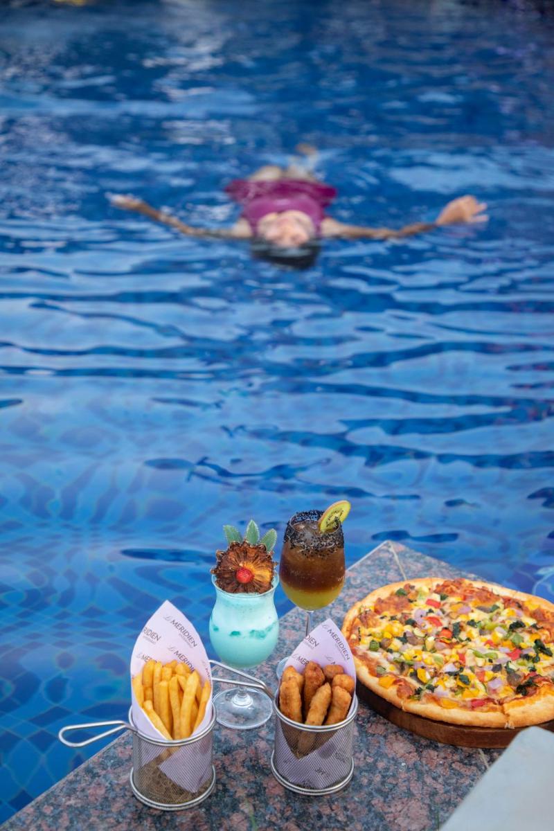 a table with food next to a swimming pool at Le Meridien Hyderabad in Hyderabad