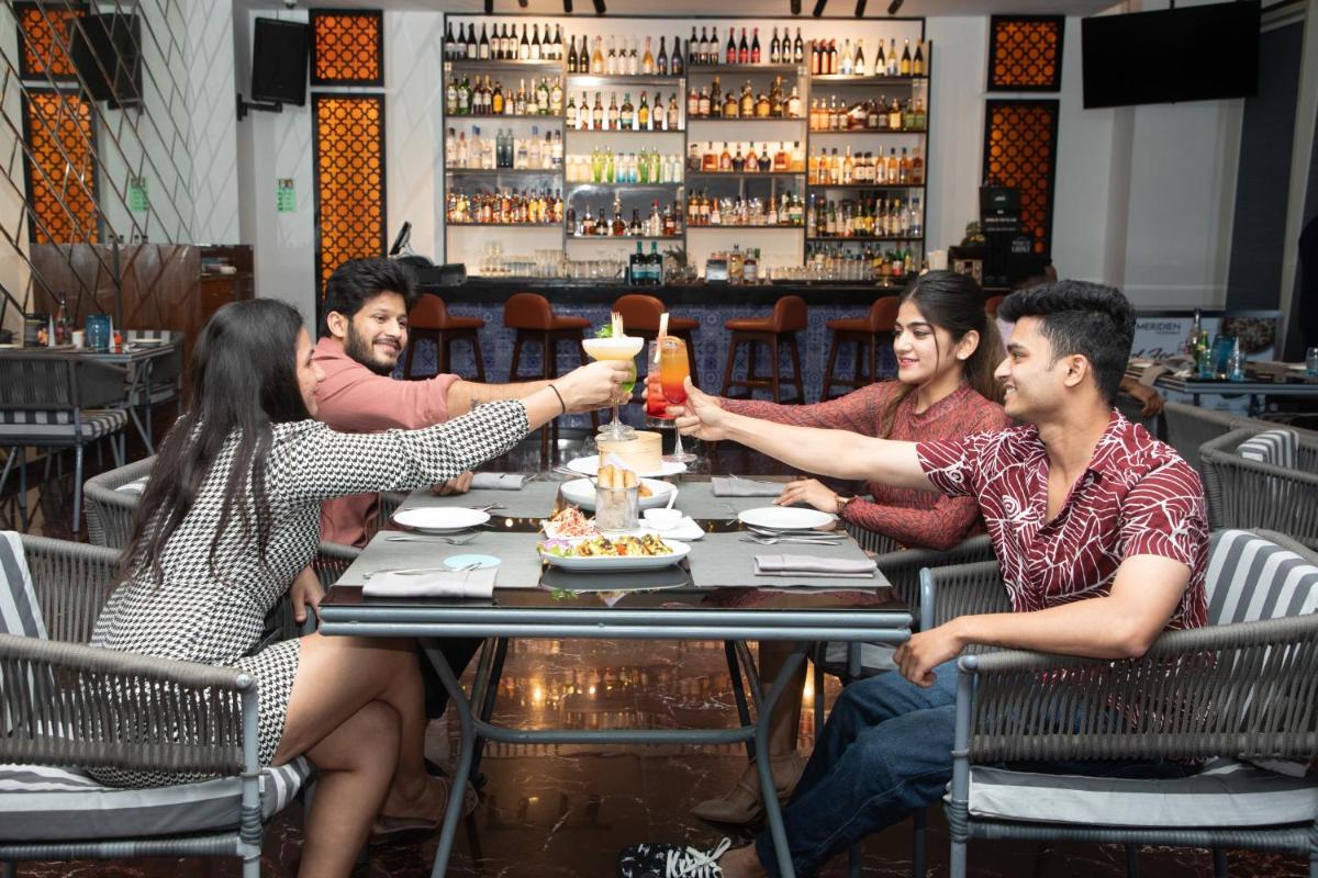 a group of people sitting around a table in a restaurant at Le Meridien Hyderabad in Hyderabad