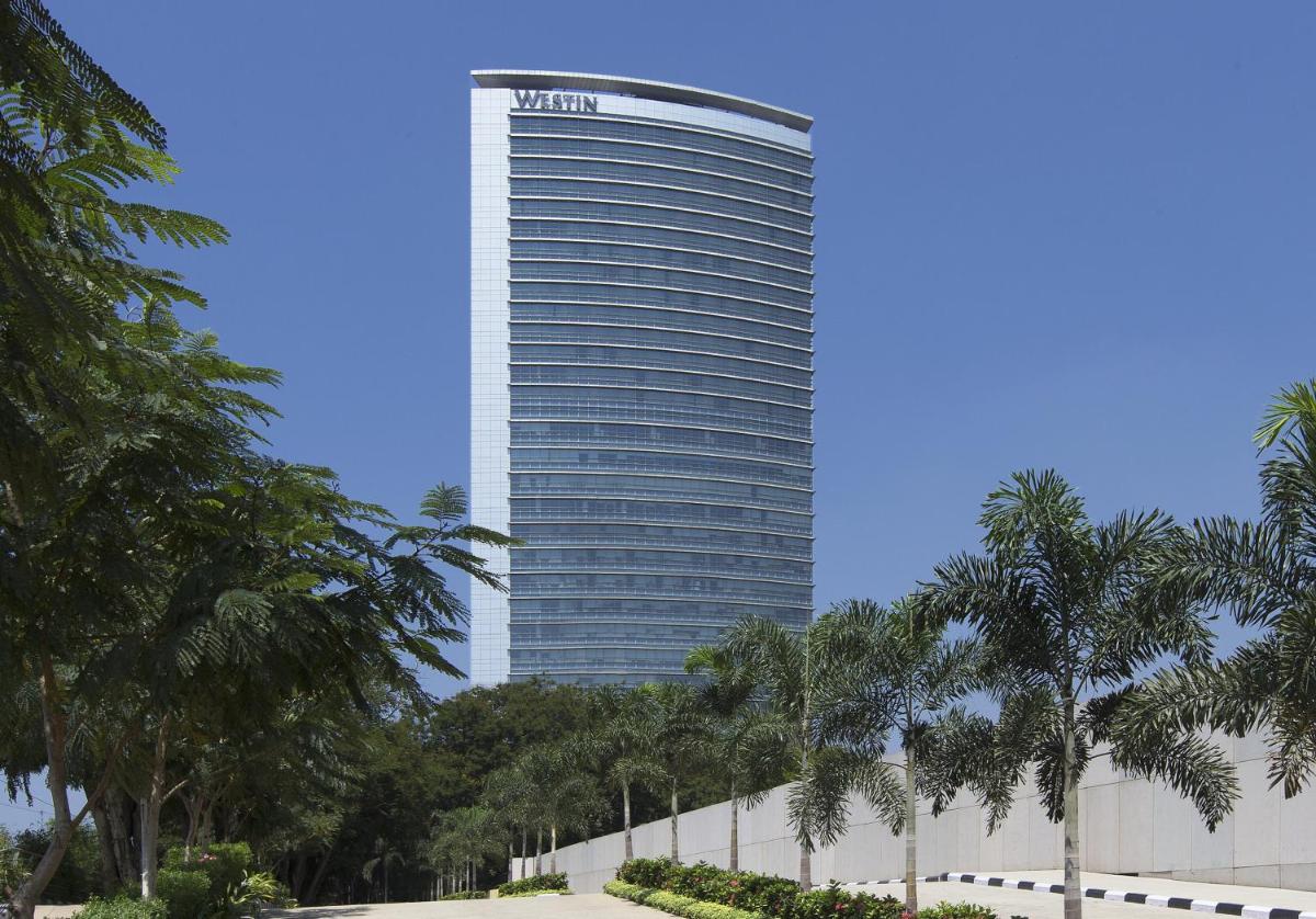 a tall building with palm trees in front of it at The Westin Mumbai Garden City in Mumbai