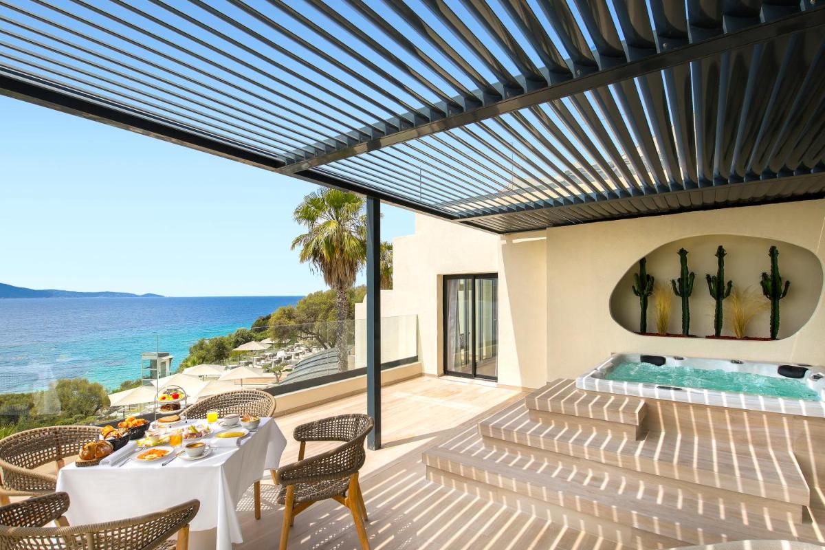 un patio avec une table et des chaises et une piscine dans l'établissement Hôtel Marinca & Spa, à Olmeto