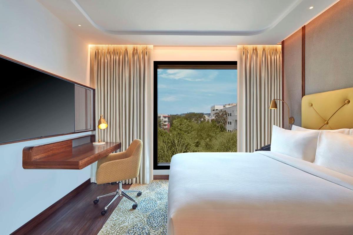 a hotel room with a bed and a desk and a television at Doubletree By Hilton Bengaluru Whitefield in Bengaluru