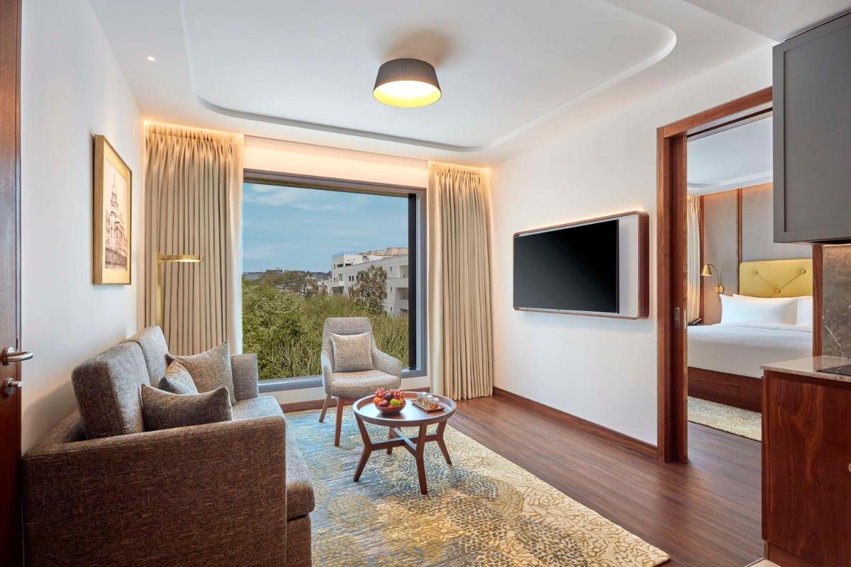 a living room with a couch and a tv and a bed at Doubletree By Hilton Bengaluru Whitefield in Bengaluru