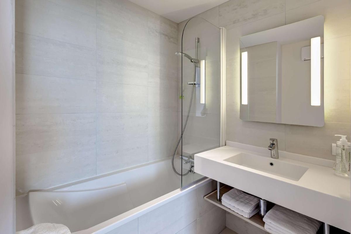 une salle de bain blanche avec un lavabo et une douche dans l'établissement Brit Hotel Vendée Mer, à La Mothe-Achard 10 autres photos