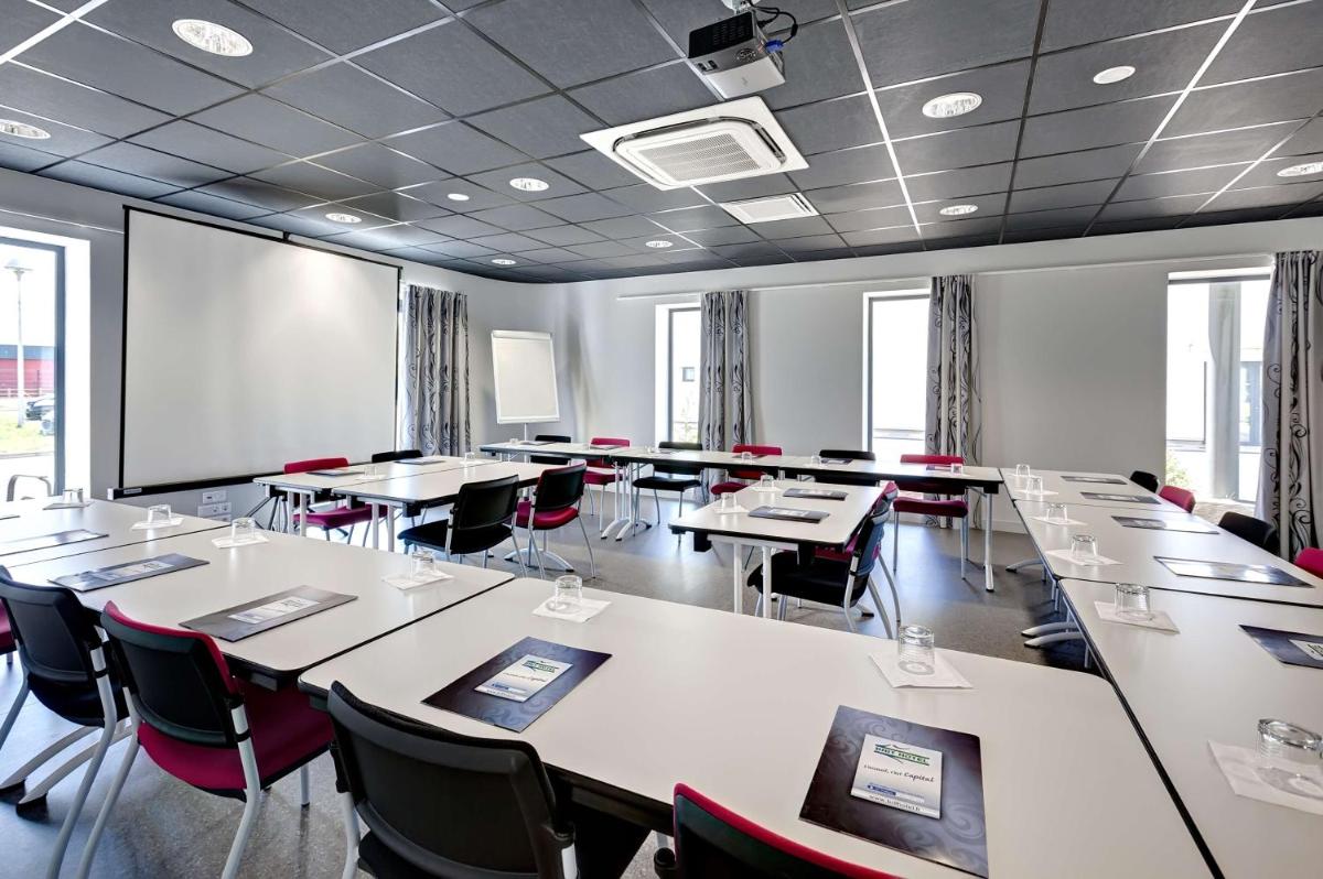 une salle de classe avec des tables et des chaises et un tableau blanc dans l'établissement Brit Hotel Vendée Mer, à La Mothe-Achard