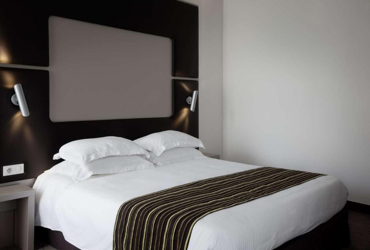 Un ou plusieurs lits dans un hébergement de l'établissement Brit Hotel de Grignan Vichy
