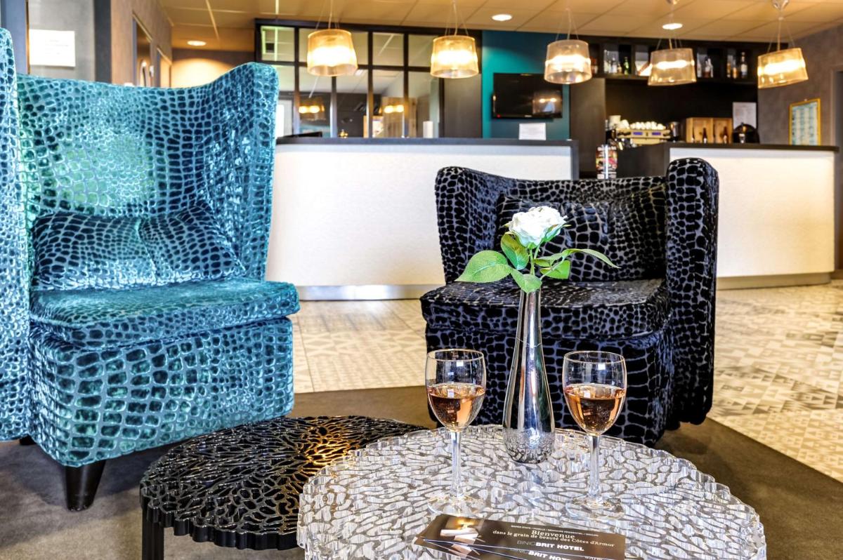 - une table avec deux chaises et deux verres de vin dans l'établissement Brit Hotel Le Galion & Spa, à Binic
