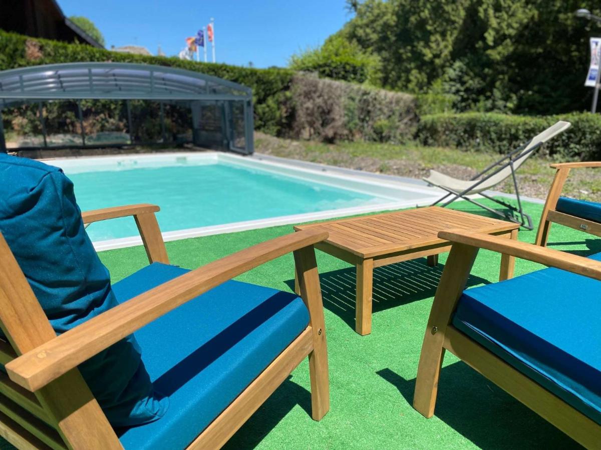 deux chaises et une table à côté d'une piscine dans l'établissement BRIT HOTEL & SPA Le Roc au Chien, à Bagnoles-de-l'Orne