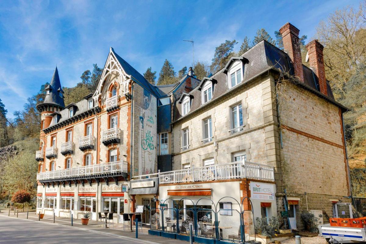 un grand bâtiment en briques sur le côté d'une rue dans l'établissement BRIT HOTEL & SPA Le Roc au Chien, à Bagnoles-de-l'Orne