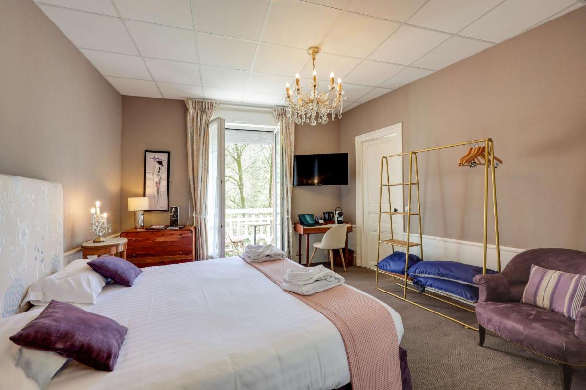 une chambre avec un grand lit et une chaise dans l'établissement BRIT HOTEL & SPA Le Roc au Chien, à Bagnoles-de-l'Orne