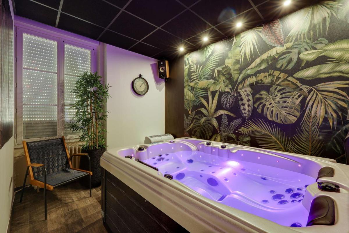 une salle de bain violette avec une grande baignoire violette dans l'établissement BRIT HOTEL & SPA Le Roc au Chien, à Bagnoles-de-l'Orne