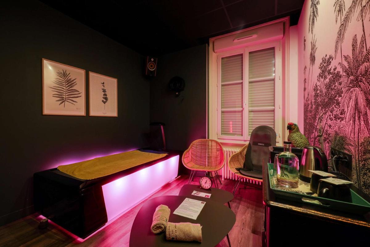 Cette chambre comprend deux lits et une table avec des lumières roses. dans l'établissement BRIT HOTEL & SPA Le Roc au Chien, à Bagnoles-de-l'Orne