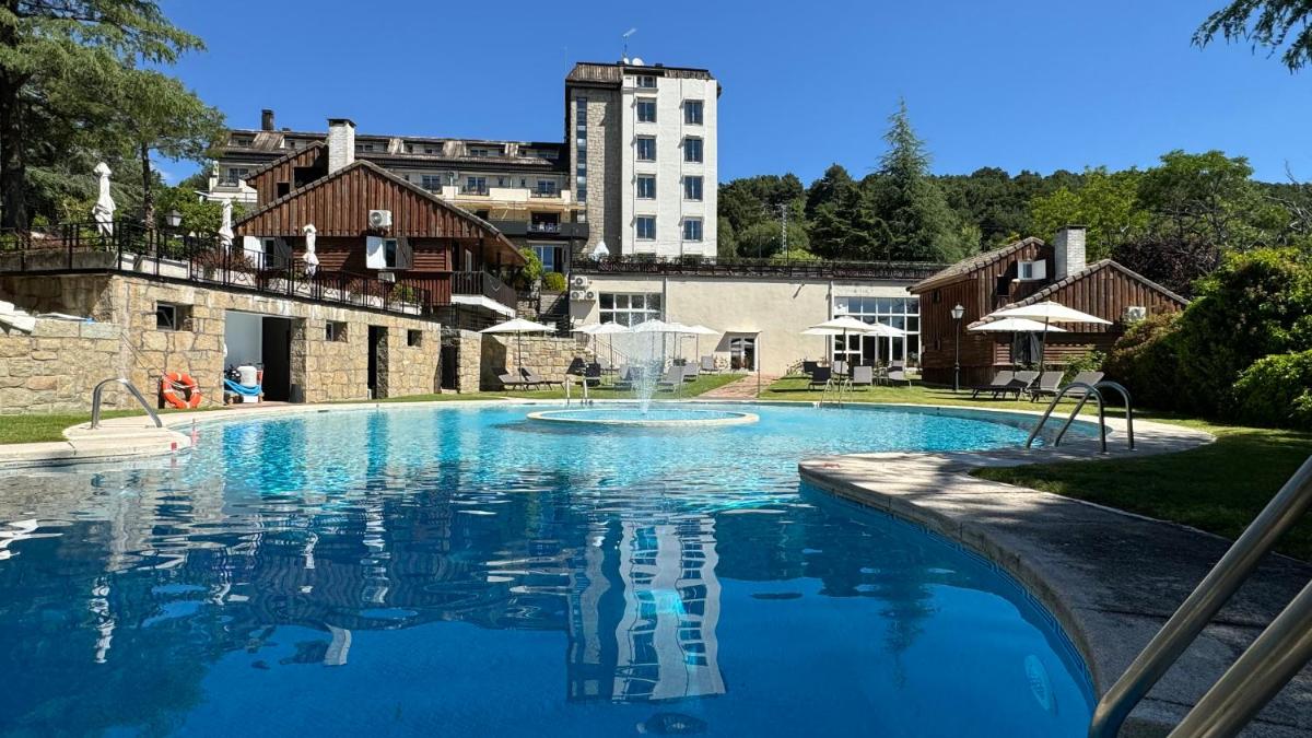 Una gran piscina con un edificio al fondo. en Hotel Hita "Nature Experience" for all, en Navacerrada