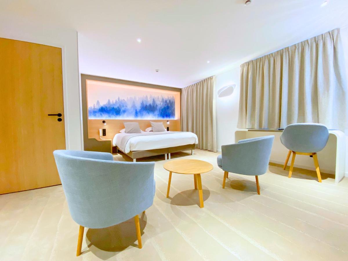 une chambre d'hôtel avec un lit et deux chaises dans l'établissement Brit Hotel Piscine & Spa - Fougères, à Lécousse