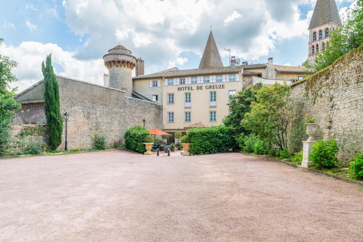 un grand bâtiment avec un château en arrière-plan dans l'établissement Demeures & Châteaux - Hôtel Greuze & Spa Tournus, à Tournus
