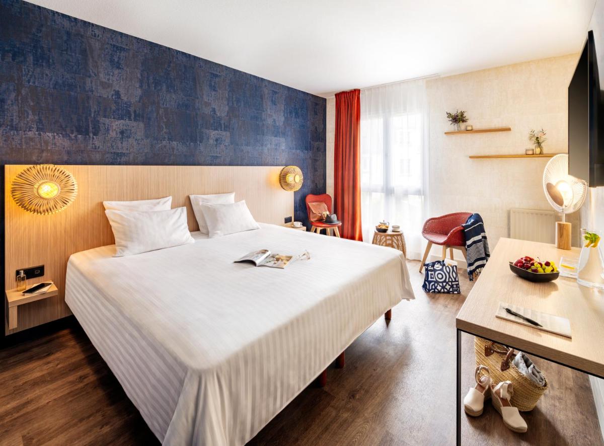 une chambre d'hôtel avec un grand lit blanc et un bureau dans l'établissement Hôtel L'Escale Marine Valdys Resort & SPA, à Douarnenez