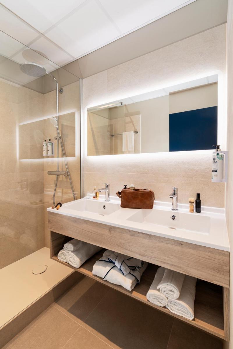 une salle de bain avec un lavabo, un miroir et des serviettes dans l'établissement Hôtel L'Escale Marine Valdys Resort & SPA, à Douarnenez