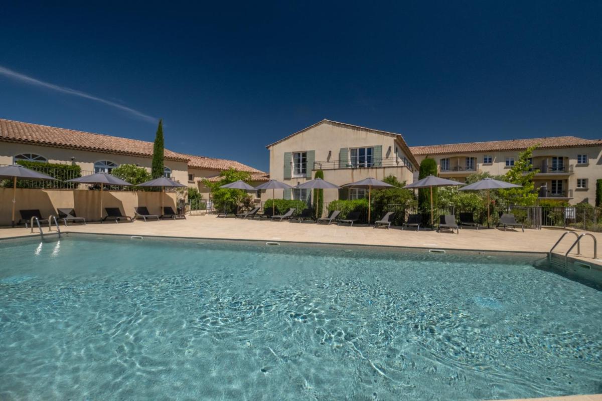 - une piscine en face d'un bâtiment avec des parasols dans l'établissement Le Domaine de Saint Endreol Golf & Spa Resort, à La Motte